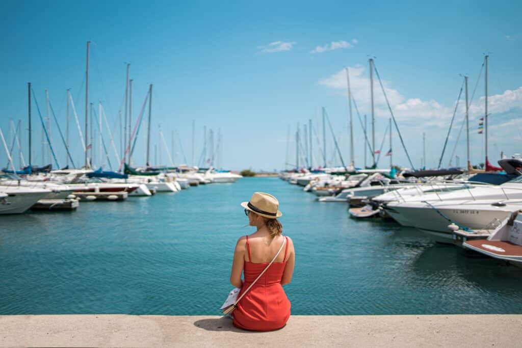Image of a woman sitting on the water's edge at one of Chicago's many harbors.