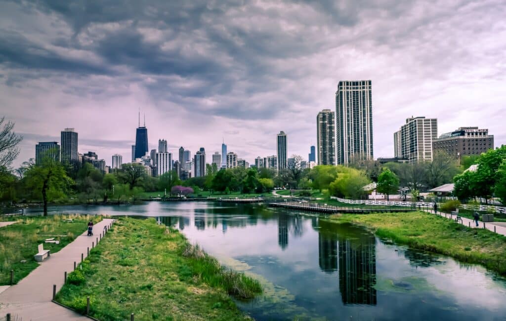 Picture of Lincoln Park in Chicago in the spring with green grass and the reflection of the skyline on a pond.