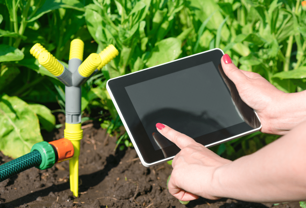 Image of a smart sprinkler and someone controlling it with a tablet